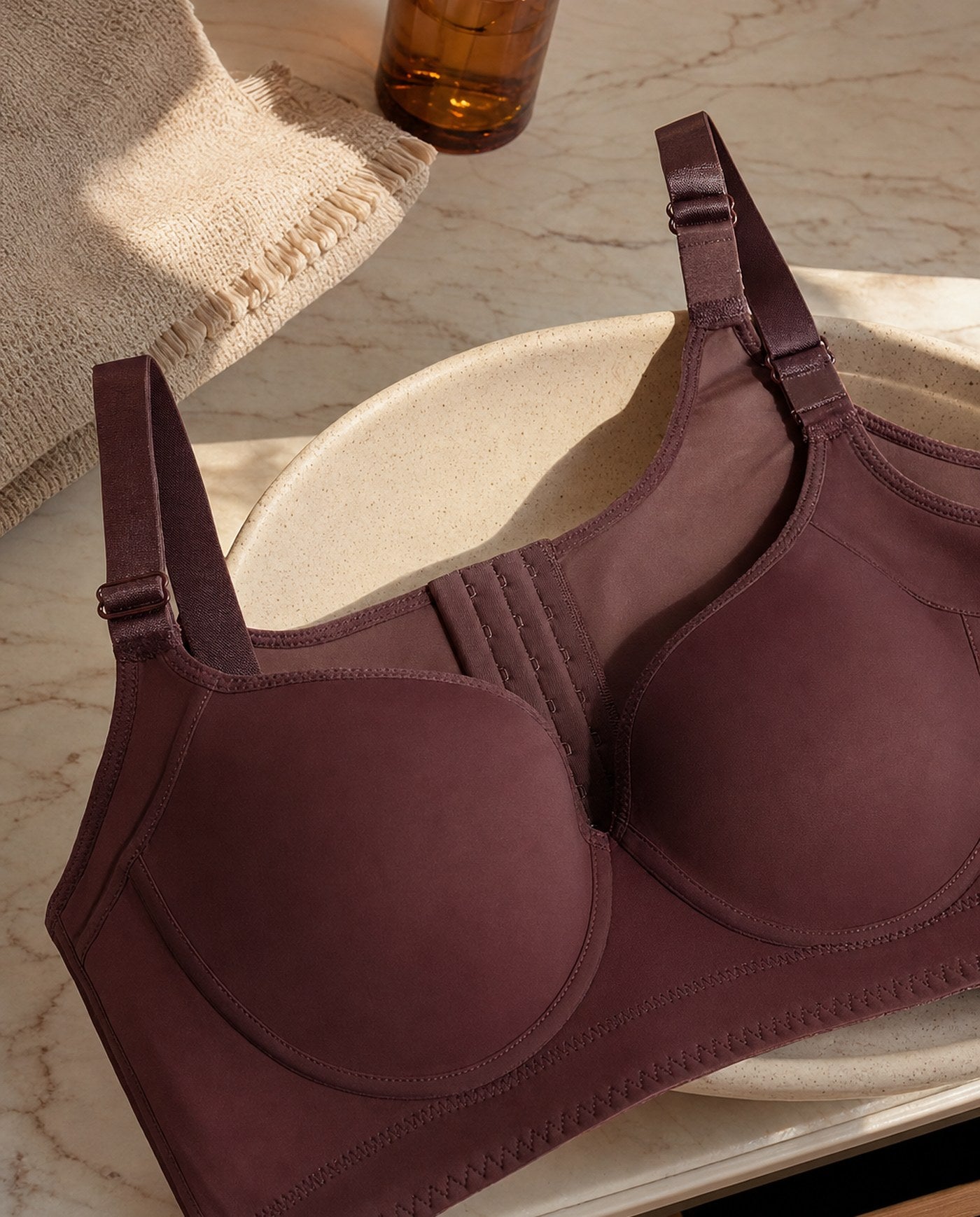 The Ease wireless smoothing bra in Burgundy on a pale marble vanity