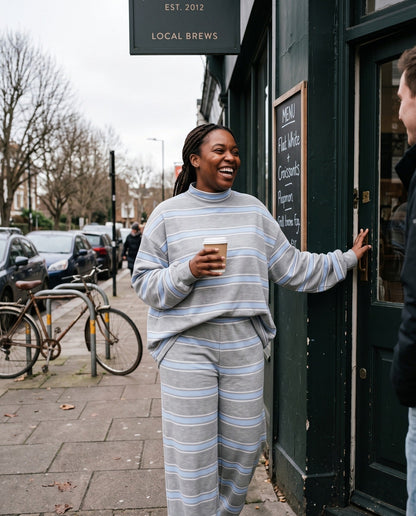 A woman leaving a neighborhood coffee shop in The Sunday striped lounge set in Gray