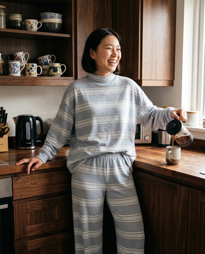 A woman pouring coffee in her kitchen in The Sunday striped lounge set in Light Blue