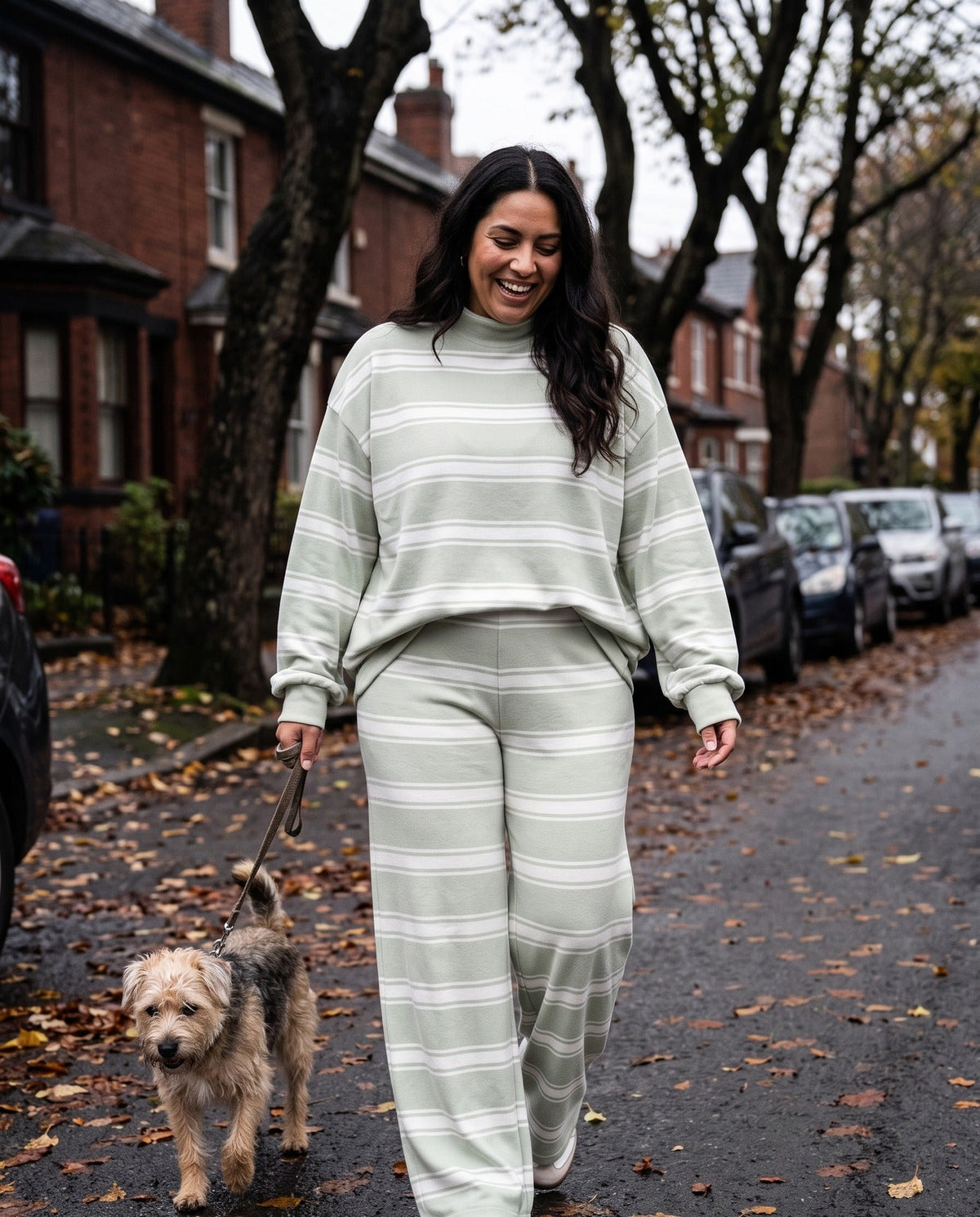 A woman walking her dog down a tree-lined street in The Sunday striped lounge set in Grass Green