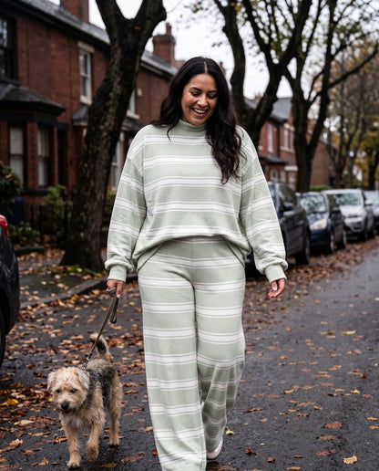 A woman walking her dog down a tree-lined street in The Sunday striped lounge set in Grass Green